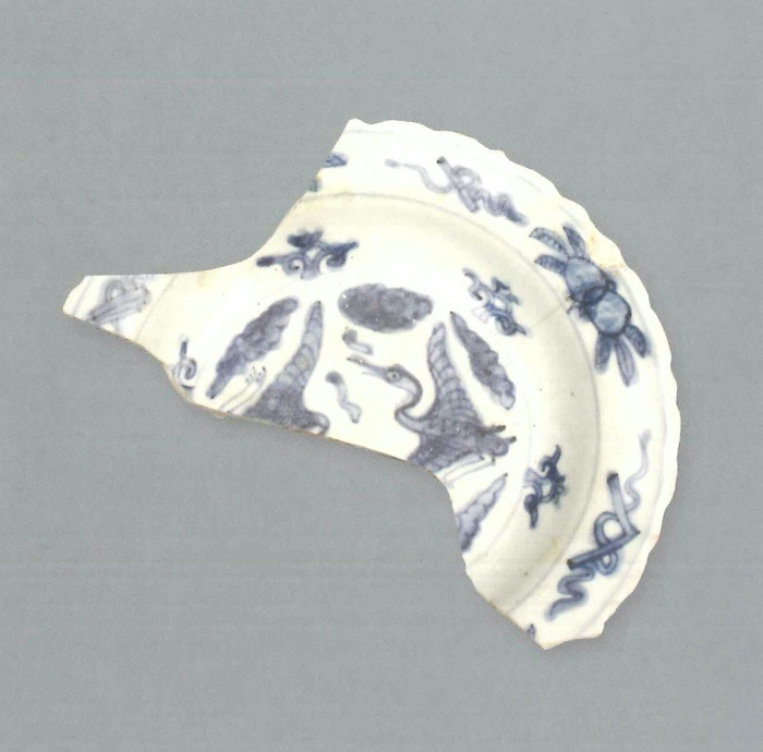 【青花瓷器】澳門出土的青花雙鶴紋折沿盤(殘)
Foliated edge blue-and-white dish with pair of cranes (Shard)
萬曆早中期(Early to Middle Wanli)
口徑(MD) 18.2cm， 足徑(FD) 10.8cm，高(H) 2.8cm
胎質緻密，釉泛青灰。青花發色較淡，藍中微泛灰。繪畫手法細膩，盤心飾雙鶴祥雲紋，盤沿較窄，飾雜寶紋，腹留白。外壁腹留白,沿邊繪花草紋。外底青花單圈內繪文字款。
