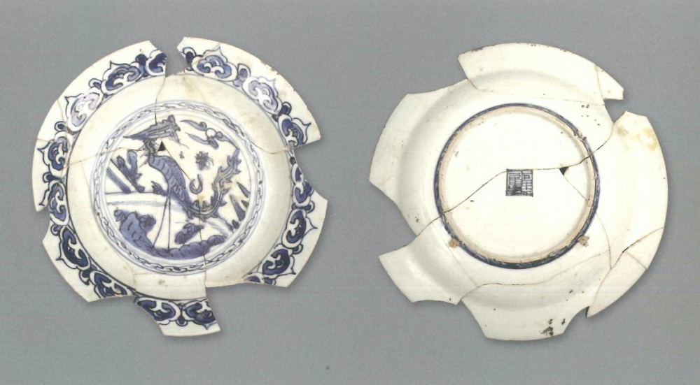 【青花瓷器】澳門出土的青花鳳紋折沿盤(殘)
Foliated edge blue-and-white dish with phoenix design (Shard)
萬曆中期([Middle Wanli)
口徑(MD) 16.8cm， 足徑(FD) 11.8cm，高(H) 2.4cm
胎質緻密細白，釉泛青。青花發色分布不均，有的較鮮豔，藍中微泛紫;有的發色較淡，藍中微泛灰。此殘盤較為完整，盤心裝飾鳳紋，腹留白，沿面繪祥雲紋;外壁腹及沿邊無裝飾。外底青花方形內繪文字款。圈足有窯粘。此盤是嘉靖至萬曆時期常見的盤，當時大量出口，很多國外博物館都能見其蹤影，在新近發現的廣東南澳1號沉船中也有類似的作