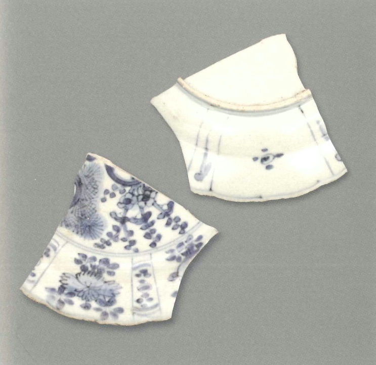 【青花瓷器】澳門出土的青花花卉紋折沿小盤(殘)
Foliated edge blue-and-white saucer dish with flower design (Shard)
萬曆晚期(LateWanli)
口徑(MD)18.2cm，足徑(FD)14.8cm，高(H)3.2cm
胎質緻密，釉泛青灰。青花發色較淡，藍中微泛灰。繪畫手法細膩，盤心飾繪梅花、松樹等，也許是松竹梅“歲寒三友”圖。盤內壁的大開光內繪牡丹、石榴等，這些大開光之間有小開光，里面有圓點等。外壁的大開光之間也有小開光，大開光內為簡化的花朵，小開光內有一蝌蚪形飄帶。這些開光裝飾在克拉克瓷盤外壁頗為常見。盤沿及外壁飾瓔珞雜寶